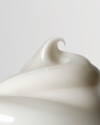 Close-up of a smooth, white ceramic object with a wavy design on a light gray background