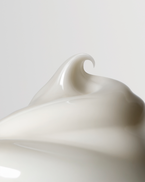 Close-up of a smooth, white ceramic object with a wavy design on a light gray background