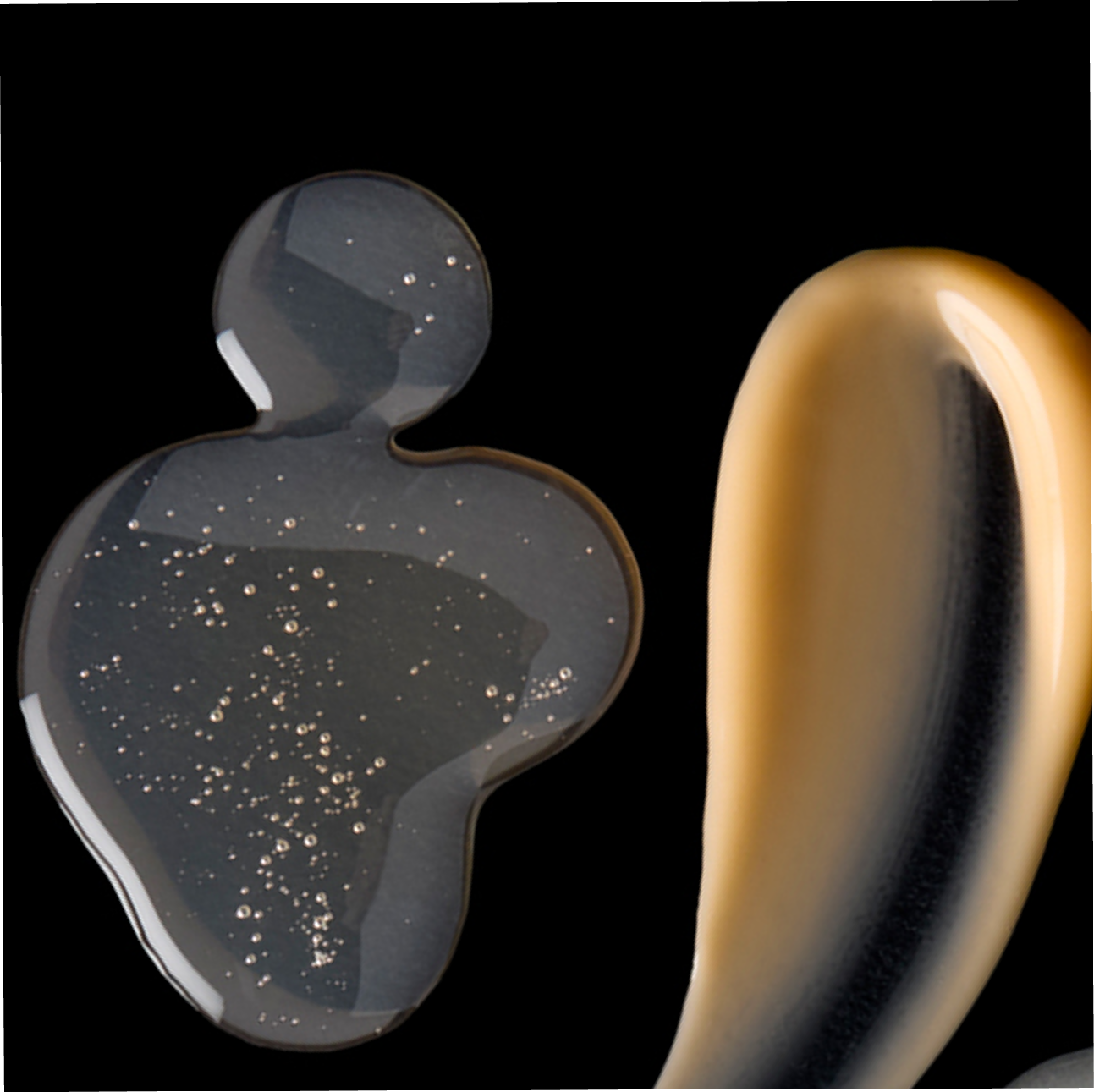 Two metallic objects, one gray and one gold, on a black background